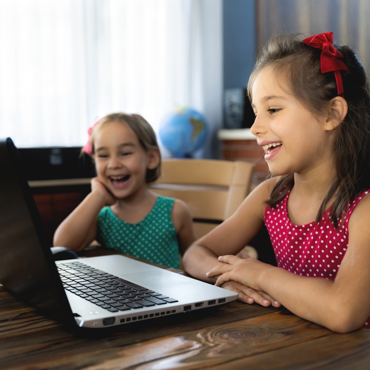 Two sisters laughing during their live online Spanish class