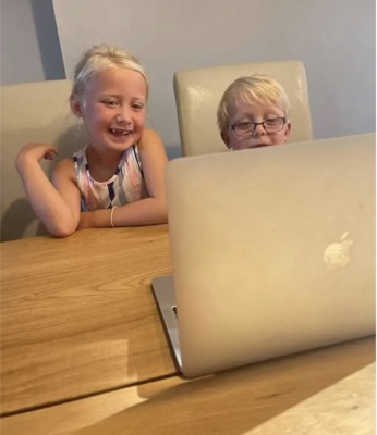 Two Diluu students smiling behind their laptop