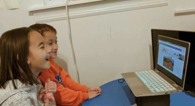 Siblings laughing during their online Spanish class