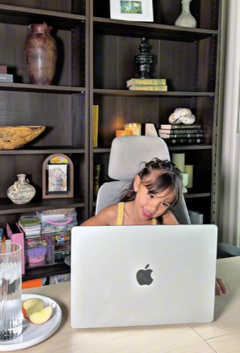 Niña divirtiéndose y asomándose por encima del portátil en su clase online de Diluu